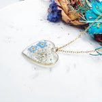 Collana artigianale ciondolo cuore con fiori veri in resina – nontiscordardimè azzurri e pizzo della regina Anna, acciaio oro
