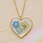 Collana artigianale ciondolo cuore con fiori veri in resina – nontiscordardimè azzurri e pizzo della regina Anna, acciaio oro