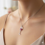 Può includere: Collana color argento con un ciondolo a forma di calice di vino. Il calice è riempito con una sostanza rosso scuro. La collana è indossata al collo.